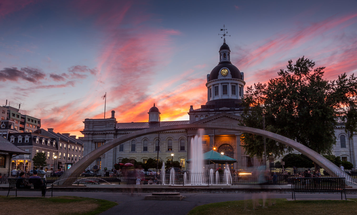 The Kingston, Ontario City Hall illuminated by the evening sun, with a reflection of its iconic architecture in the water below.